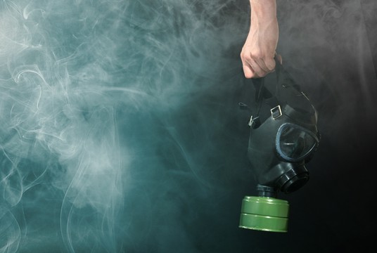 ręka trzymająca maskę gazową w dymie